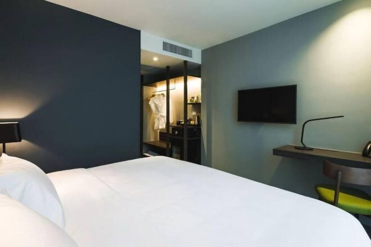 Ein Hotelzimmer mit Bett, Schreibtisch, Stuhl, Fernseher und begehbarem Kleiderschrank.