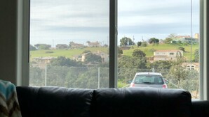 A living room with a large window overlooking a residential area and a parked car. - Luxury Pismo Beach condo close to shopping and mins drive to the beach. (Pismo Beach)