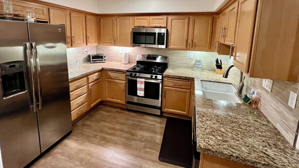 A modern kitchen with stainless steel appliances, wooden cabinets, and granite countertops. - Luxury Pismo Beach condo close to shopping and mins drive to the beach. (Pismo Beach)