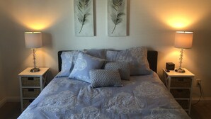 A bedroom with a bed, two nightstands, two lamps, and two feather art pieces on the wall. - Luxury Pismo Beach condo close to shopping and mins drive to the beach. (Pismo Beach)