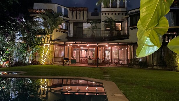 A large, multi-story building with a well-lit patio area and a swimming pool.