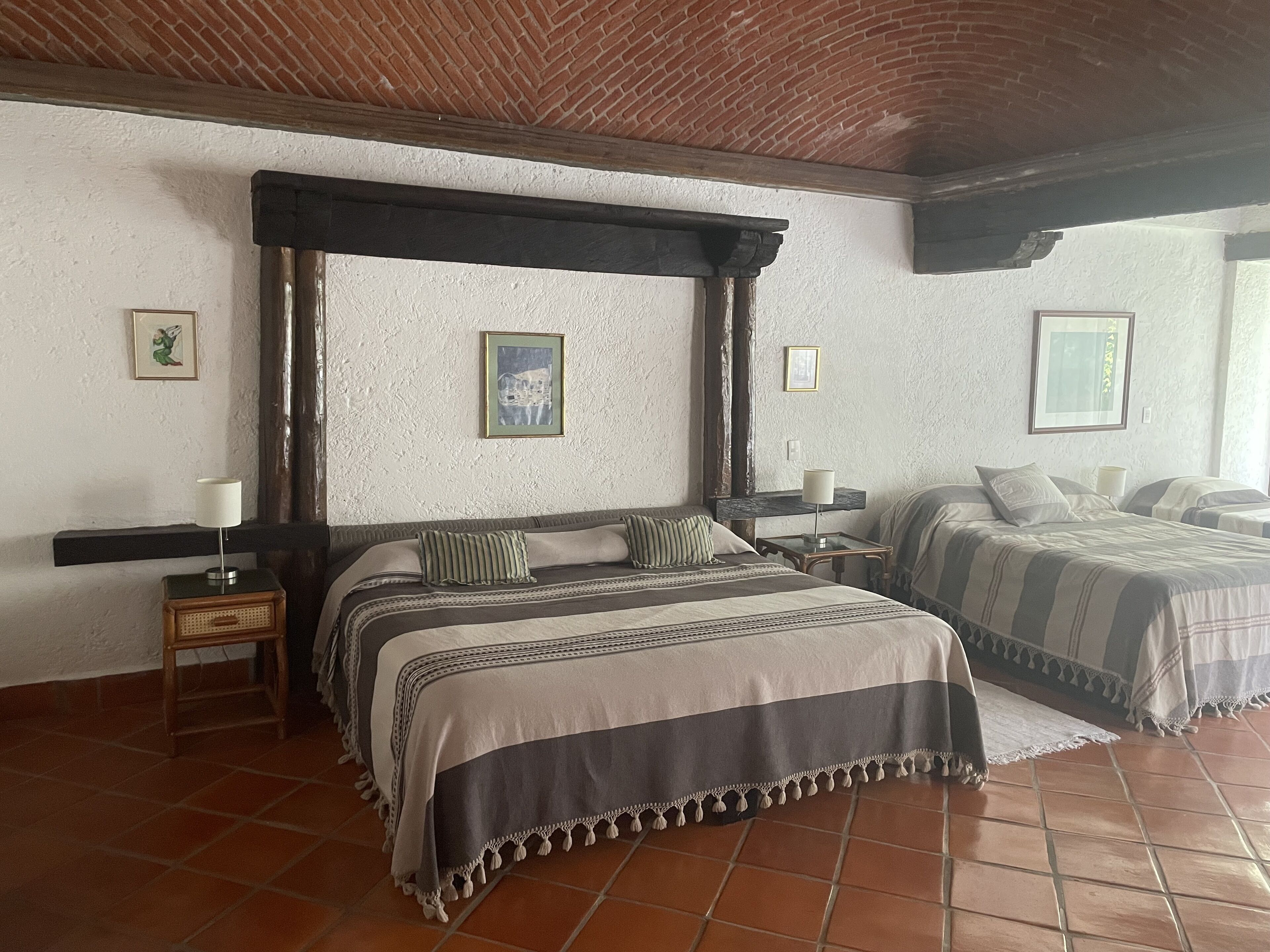 Un dormitorio con una cama con dosel, dos mesitas de noche y un ventanal grande.