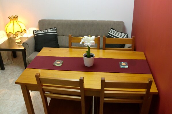 A dining table with a flower vase, two candles, and a red placemat. - The Yellow House 3 :) (Porto)