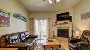 A living room with a leather sofa, a coffee table, a fireplace, and a television. - Go with the Flow! CW B103 by RedAwning (New Braunfels)