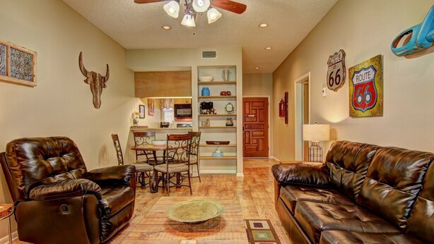A living room with leather sofas, a dining area with a wooden table and chairs, and a kitchen in the background. - Go with the Flow! CW B103 by RedAwning (New Braunfels)