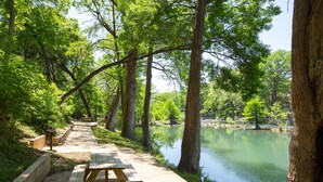 A picnic table by a calm lake surrounded by tall trees. - Parker River Haus Vg106 3 Bedroom Condo by RedAwning (New Braunfels)