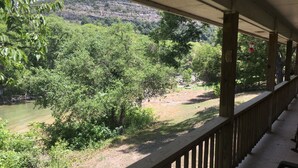 A covered outdoor area with a view of a river and surrounding greenery. - Guadalupe River Rock Retreat 9740 by RedAwning (New Braunfels)
