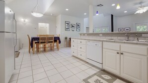 A modern kitchen with white cabinetry, a dining area with a table and chairs, and recessed ceiling lighting. - Guadalupe River Rock Retreat 9740 by RedAwning (New Braunfels)