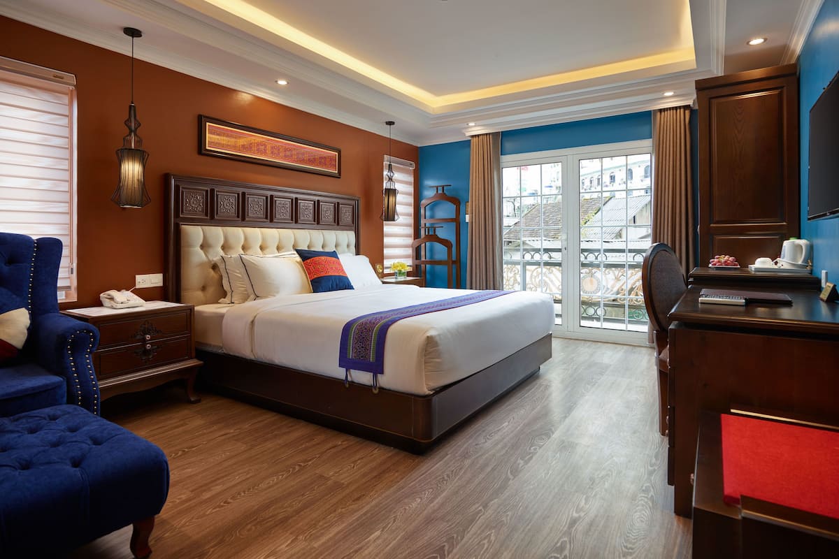 Een hotelkamer met een groot bed, een bureau met een computer, een stoel en uitzicht op de stad.
