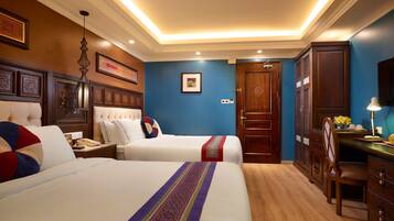 A hotel room with two beds, a desk, a chair, and a wardrobe.