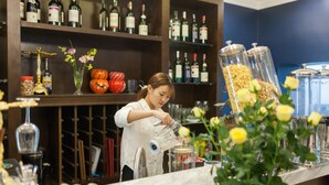 A bar area with shelves of bottles, a counter with a woman pouring a drink, and decorative items like pumpkins and flowers. - Eden Boutique Hotel & Spa (Sa Pa)