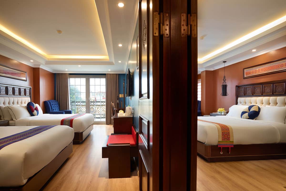 Een hotelkamer met twee bedden, een bureau, een stoel en een balkon met uitzicht.