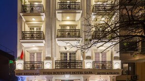 A multi-story hotel with a grand entrance, balconies, and a sign indicating it offers a restaurant, boutique, and travel services. - Eden Boutique Hotel & Spa (Sa Pa)
