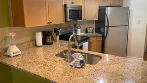 Eine Küche mit Granit-Arbeitsplatten, Edelstahlgeräten, Holzschränken, einer eingebauten Mikrowelle und einem Edelstahl-Kühlschrank.