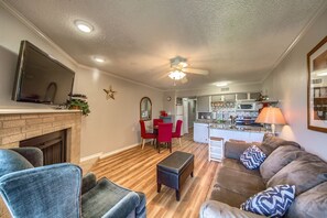 Cozy living room with a fireplace, sofa, and dining area, featuring a flat-screen TV and kitchen.