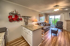Cozy living space with a kitchen area and seating area, featuring an island and a gray sofa.