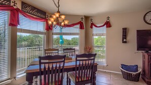 A dining area with a table and chairs, a chandelier, and a view of the outdoors.