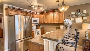 A modern kitchen with wooden cabinets, stainless steel appliances, and a granite countertop.