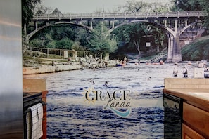 A river scene with a bridge, people, and a sign that reads "GRACE Landa". - Gracelanda Ww C302 1 Bedroom Condo by RedAwning (New Braunfels)