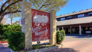 A large sign for Camp Wamego Estates with a stone pillar, a paved walkway, and a building in the background. - River Remedy CWC110 by RedAwning (New Braunfels)