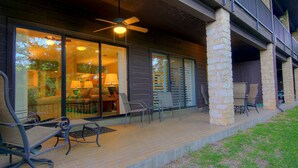 A covered patio with outdoor seating, a ceiling fan, and a view into the house through large glass doors. - River Remedy CWC110 by RedAwning (New Braunfels)