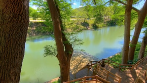 Una terraza de madera con vista a un río tranquilo y vegetación circundante.