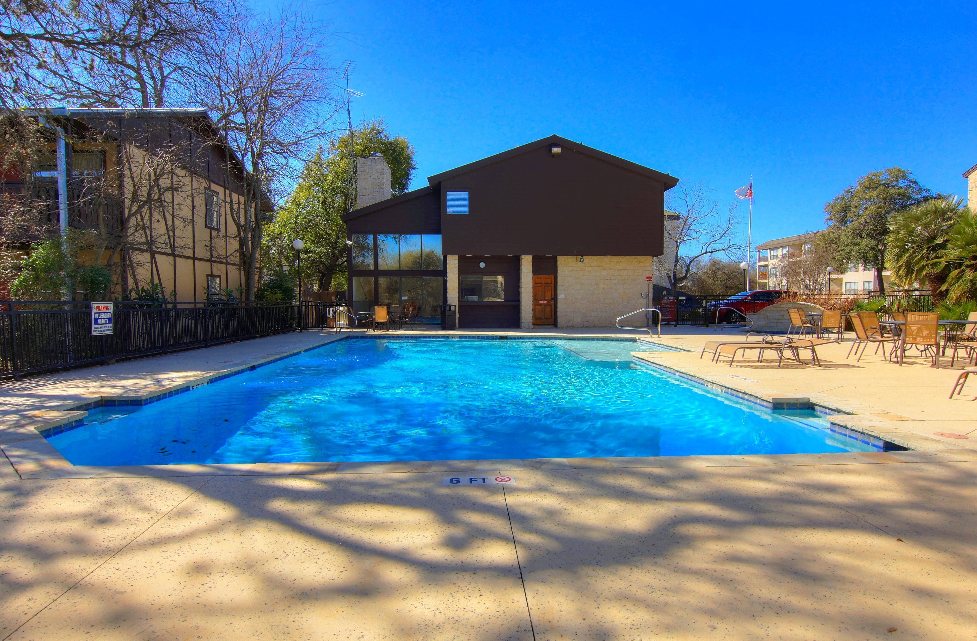 Une piscine à l’eau d’un bleu cristallin, entourée d’une terrasse en béton.