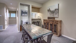 A dining area with a wooden table, chairs, a cabinet, and artwork on the walls.