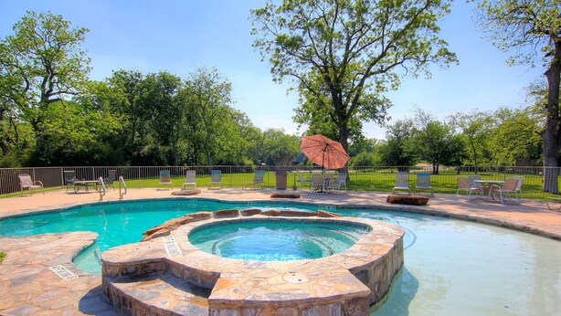 A swimming pool with a hot tub, surrounded by stone steps and lounge chairs. - River Vista Ww G302 2 Bedroom Condo by RedAwning (New Braunfels)