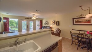 A kitchen with a dishwasher, a dining area with a table and chairs, and a ceiling fan. - River Vista Ww G302 2 Bedroom Condo by RedAwning (New Braunfels)