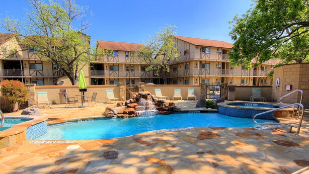 A swimming pool with a waterfall feature, lounge chairs, and a stone deck. - Guadalupe River Nut House   Ww I203 2 Bedroom Condo by RedAwning (New Braunfels)