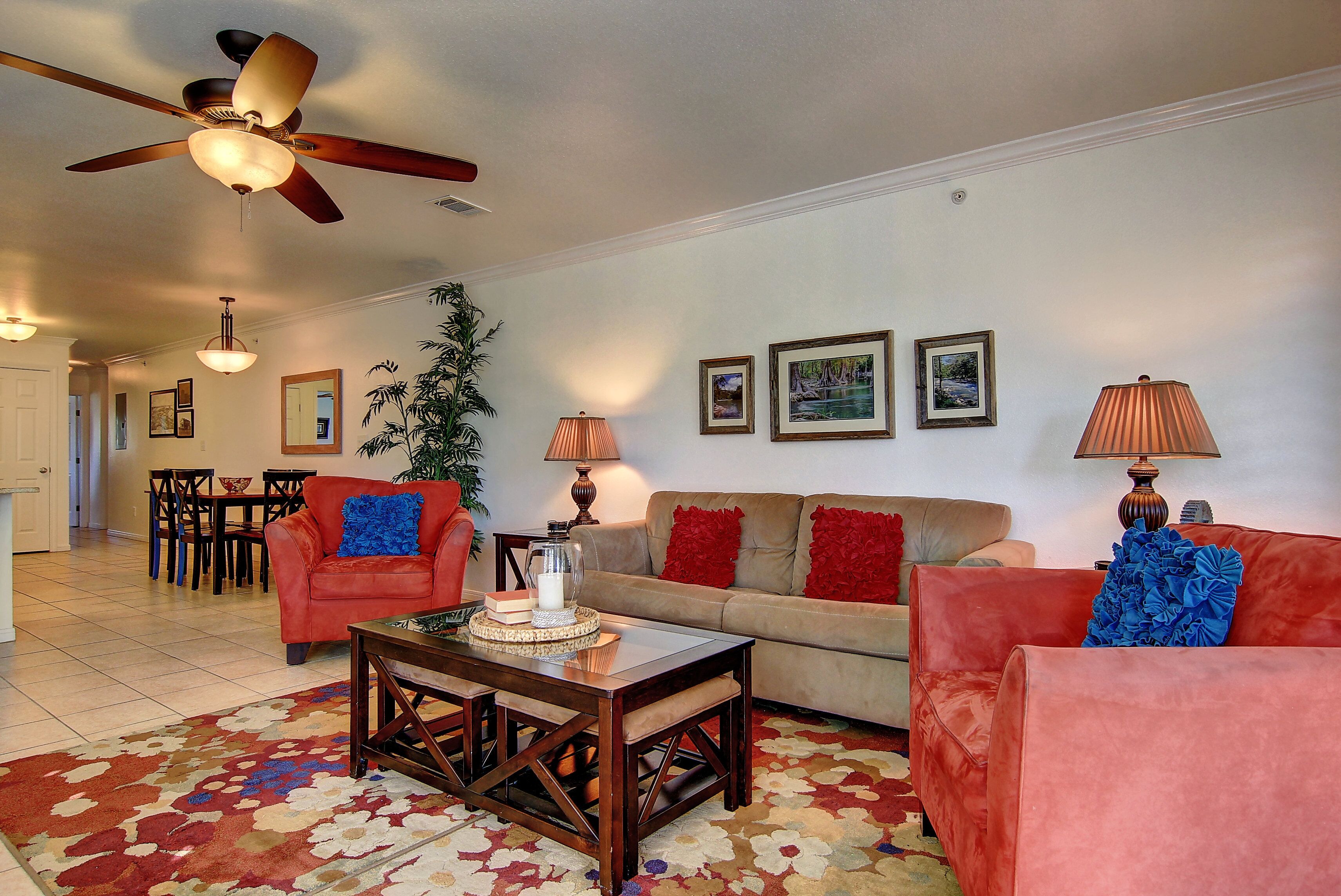 A living room with a ceiling fan, a sofa, a coffee table, and a dining area with chairs and a table.