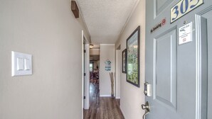 Un couloir avec un plancher en bois, une porte portant l’inscription « 303 » et un panneau indiquant « Il est interdit de fumer ».