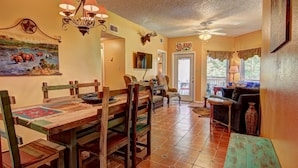 A dining area with wooden tables and chairs, a chandelier, and a painting on the wall.