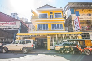 A multi-story building with a yellow facade, a visible garage, and a sign indicating it is a guest house.