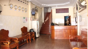 A reception area with wooden furniture, a staircase, and clocks on the wall. - Kim Guesthouse (Phnom Penh)