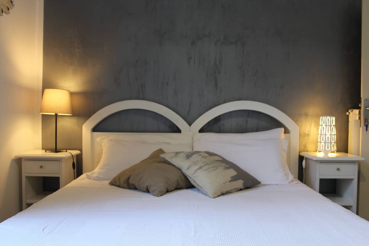 Een net opgemaakt bed met twee kussens, een bedlampje en een nachtkastje.