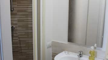 A bathroom with a shower, sink, and mirror.