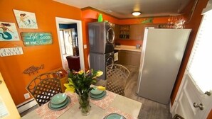 A kitchen with a dining table set for four, a refrigerator, and a washing machine.