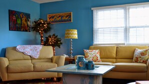 A living room with a yellow sofa, a blue coffee table, and a patterned rug.