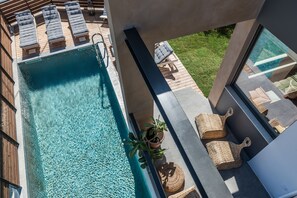 Un espace piscine aménagé sur le toit, avec des chaises longues, un pot de fleurs et des paniers en osier.