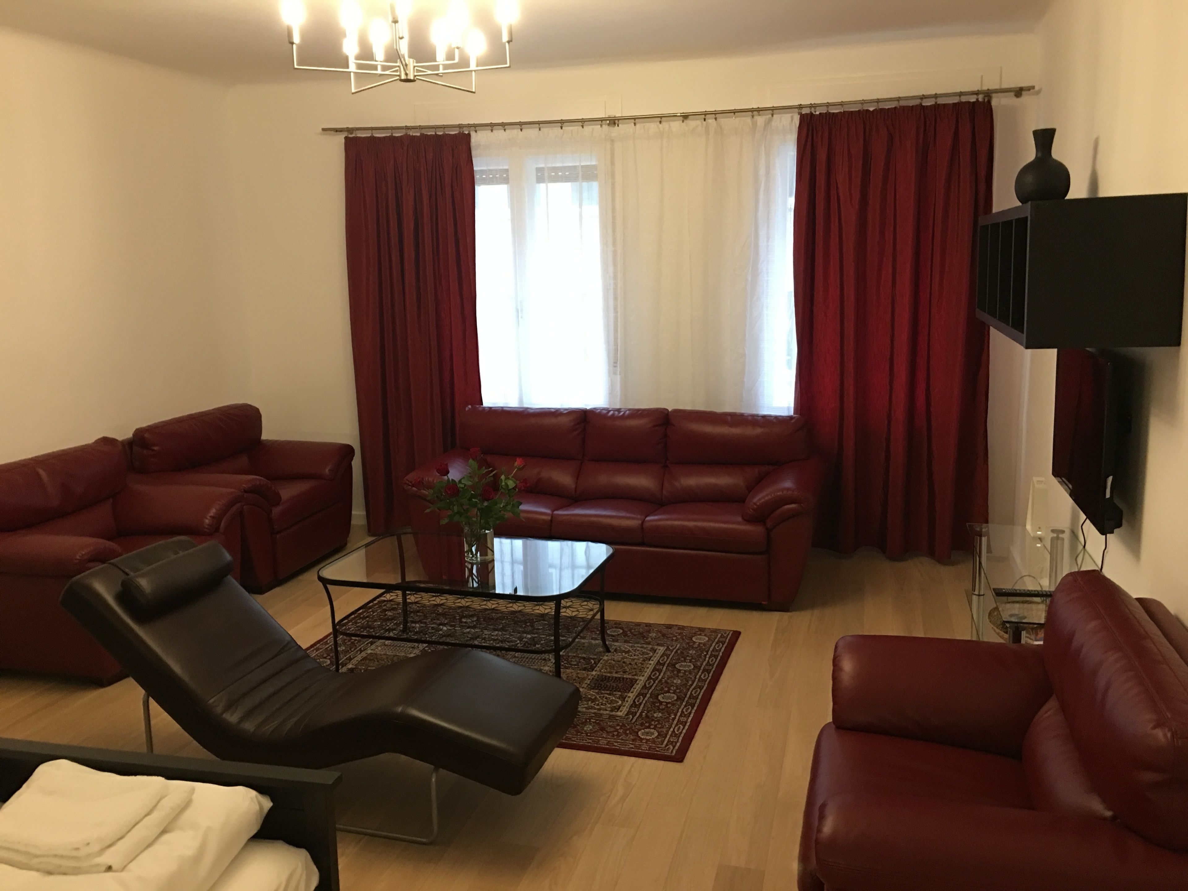 A living room with a sofa, two armchairs, a coffee table, and a TV mounted on the wall.