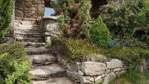Una escalera de piedra que lleva a una estructura de madera rodeada de abundante vegetación.