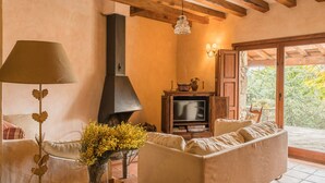Una sala de estar acogedora con chimenea, un sofá, un televisor y una lámpara.