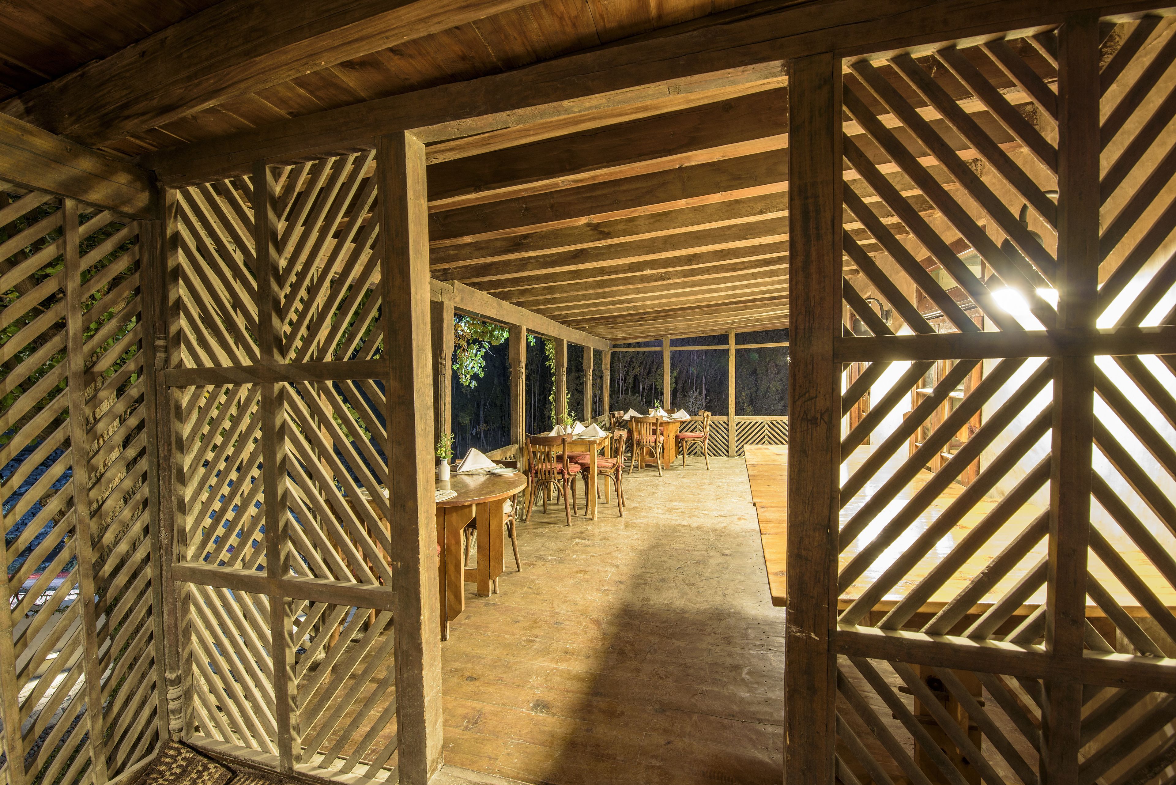 A wooden interior with a high ceiling and a central open area with tables and chairs.