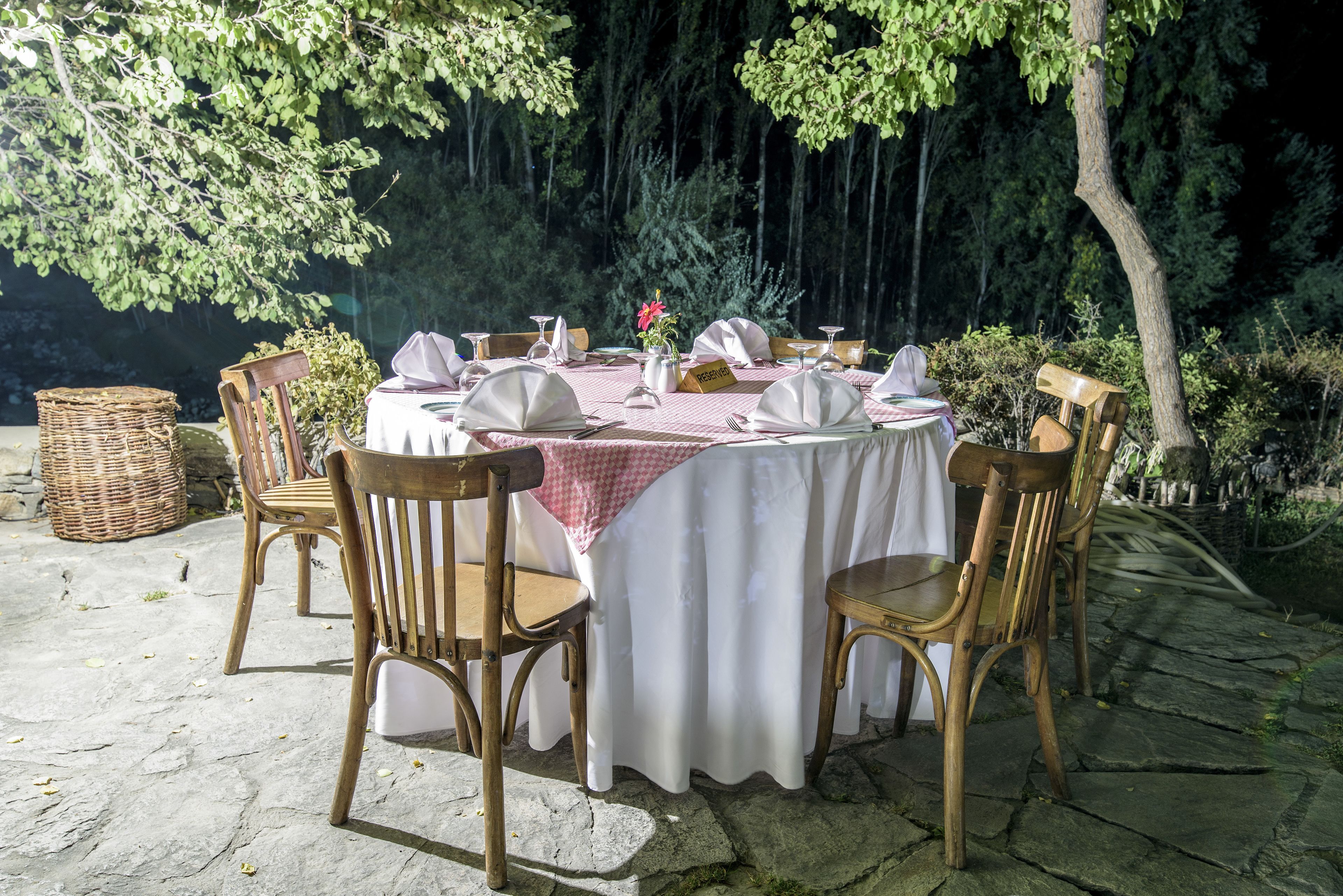 An outdoor dining area with a table set for four, surrounded by wooden chairs, and a basket to the side.