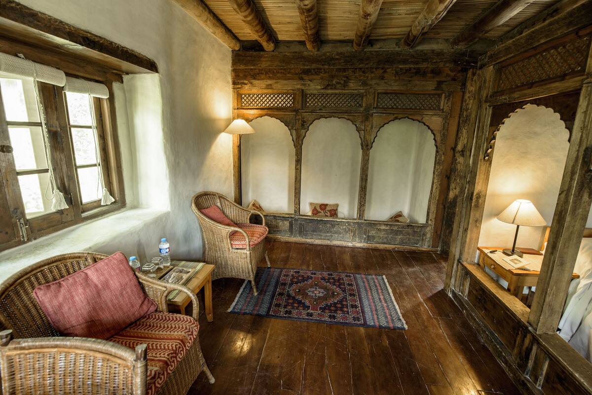 Une pièce au décor traditionnel, avec un plancher en bois, des meubles en osier et un tapis à motifs.