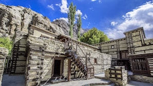 Un edificio de piedra con una escalera de madera que lleva a una entrada.