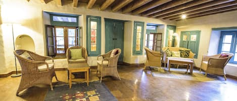 A spacious living room with wooden floors, wicker furniture, and a patterned rug.