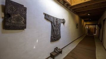 A hallway with a wooden ceiling, a bench with a pair of boots, and two artworks on the wall.